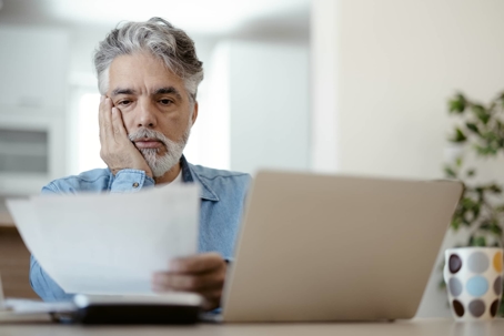 Man looking at a paper near his computer